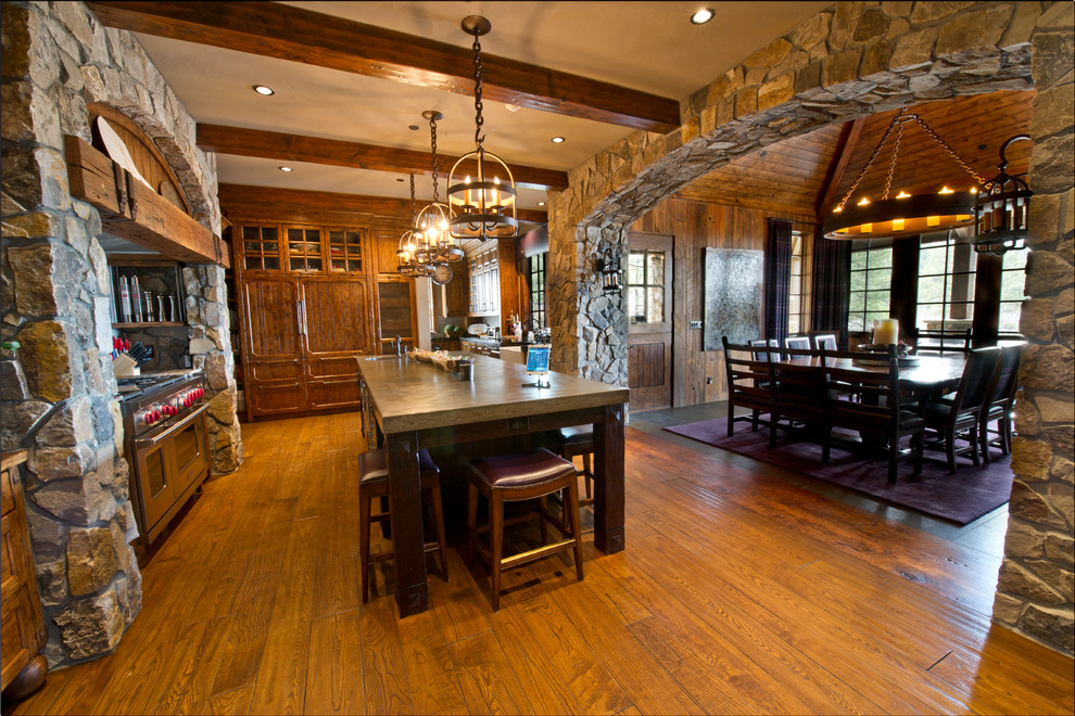 Cette photo montre une très grande salle à manger ouverte sur la cuisine montagne avec un mur marron, un sol en bois brun et un sol marron.