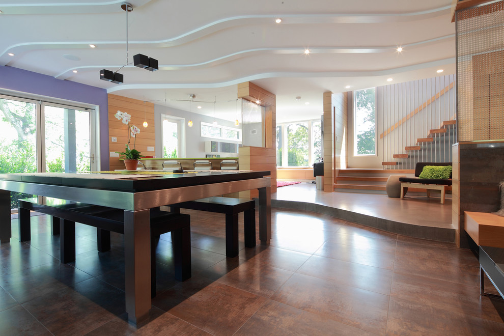 Modelo de comedor contemporáneo grande abierto con paredes púrpuras, suelo de madera en tonos medios y suelo marrón
