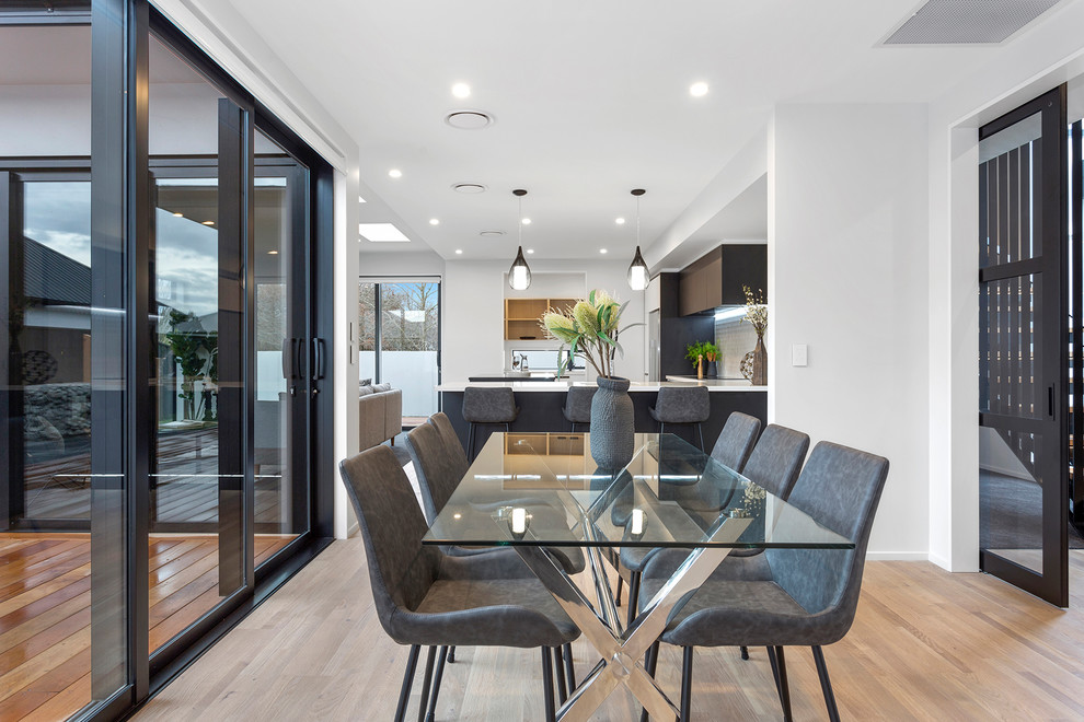 Medium sized modern kitchen/dining room in Christchurch with white walls, medium hardwood flooring and brown floors.