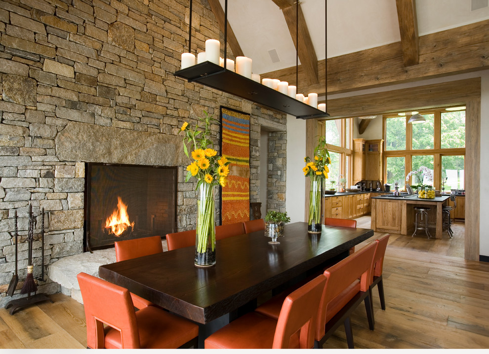 Design ideas for a rustic dining room in New York with white walls, medium hardwood flooring, a standard fireplace and a stone fireplace surround.