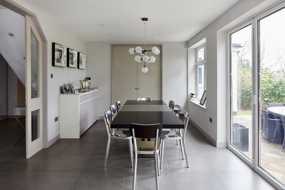 Photo of a contemporary dining room in London with white walls and grey floors.