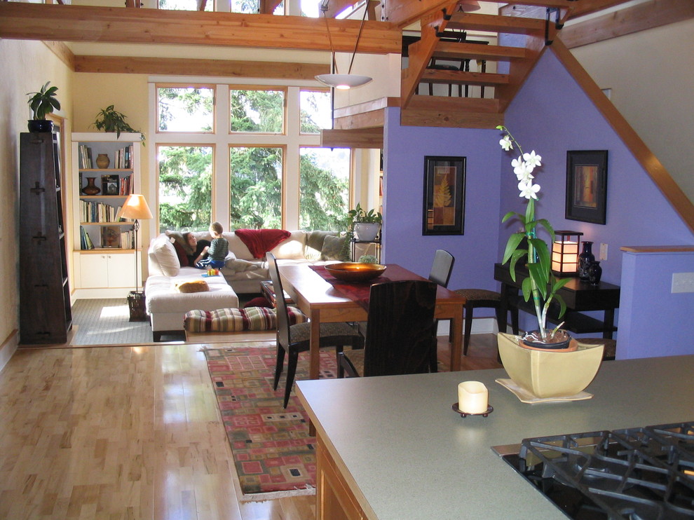 Aménagement d'une salle à manger ouverte sur le salon moderne avec un mur violet et parquet clair.