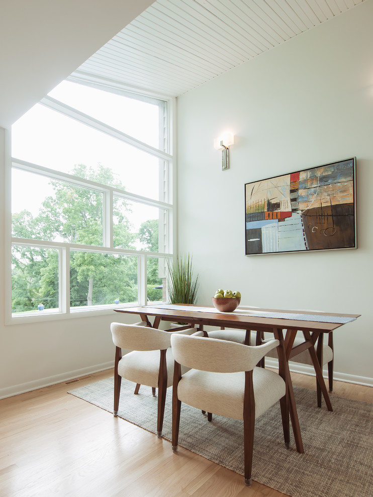Foto di una piccola sala da pranzo aperta verso la cucina minimalista con pareti bianche e parquet chiaro