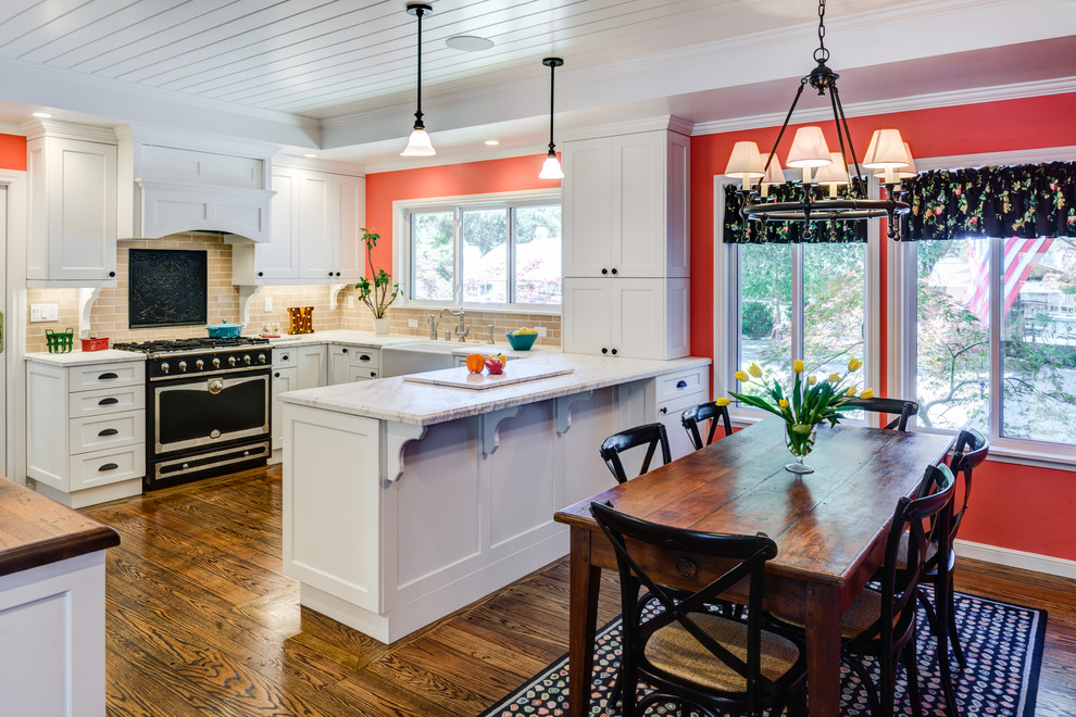 Cette image montre une salle à manger ouverte sur la cuisine traditionnelle avec un mur rouge et parquet foncé.