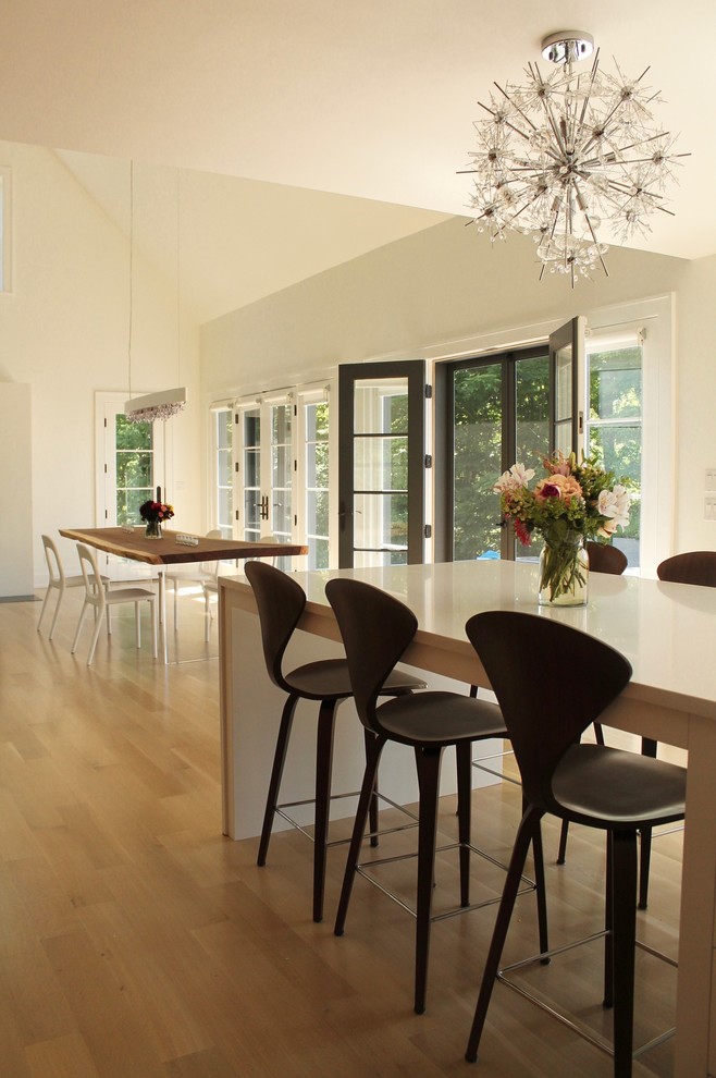 Idee per una sala da pranzo aperta verso la cucina minimalista con pareti bianche e parquet chiaro