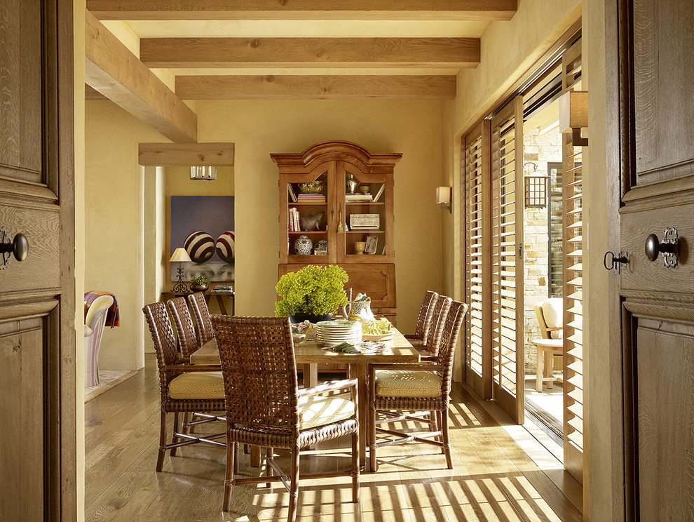Exemple d'une salle à manger méditerranéenne avec un sol en bois brun et un mur jaune.