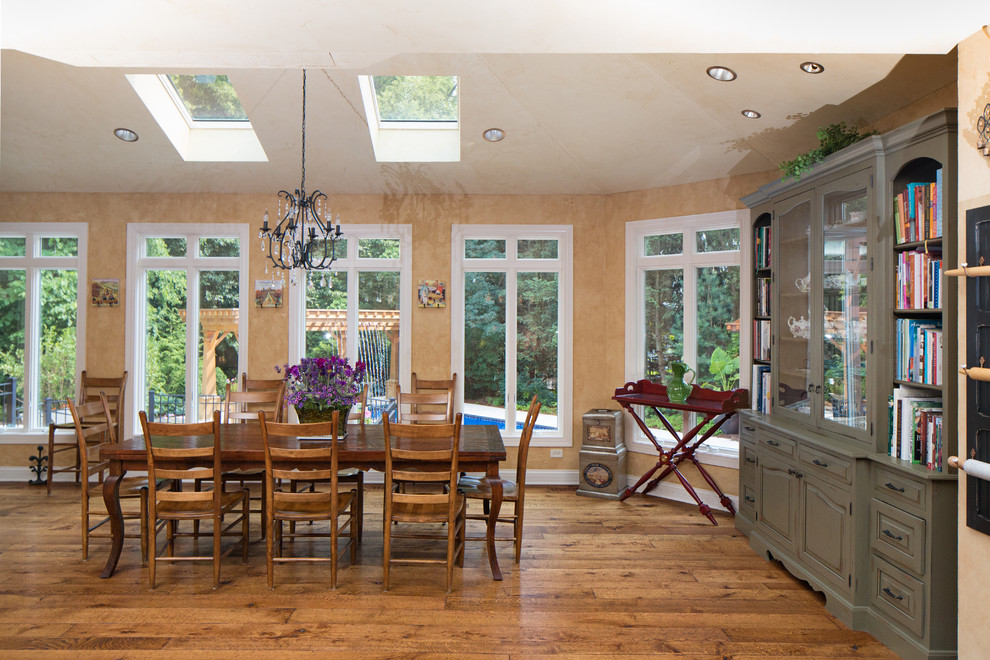 Cette photo montre une grande salle à manger ouverte sur la cuisine chic avec un mur beige et un sol en bois brun.