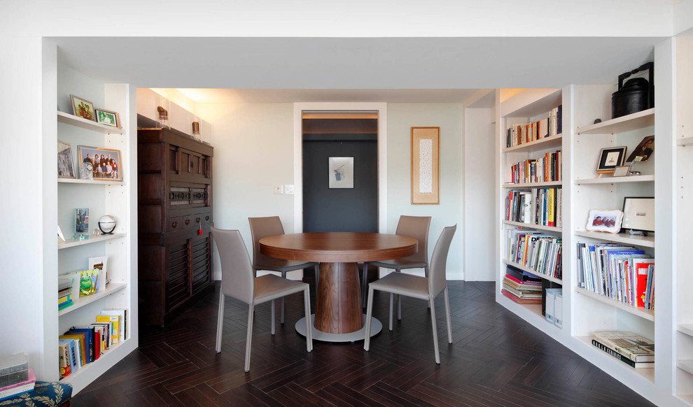 Cette photo montre une salle à manger ouverte sur la cuisine tendance de taille moyenne avec parquet foncé, un mur blanc et un sol marron.