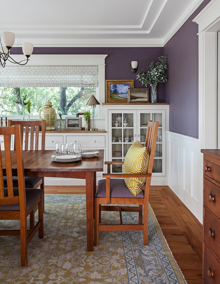 Cette image montre une salle à manger traditionnelle fermée avec un mur violet, parquet foncé, un sol marron et éclairage.