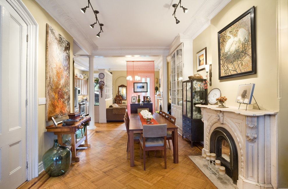 Idée de décoration pour une salle à manger tradition avec un mur beige, un sol en bois brun et une cheminée standard.