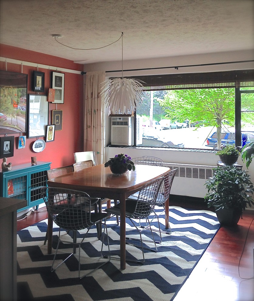Idées déco pour une petite salle à manger ouverte sur la cuisine éclectique avec un mur rouge et un sol en bois brun.