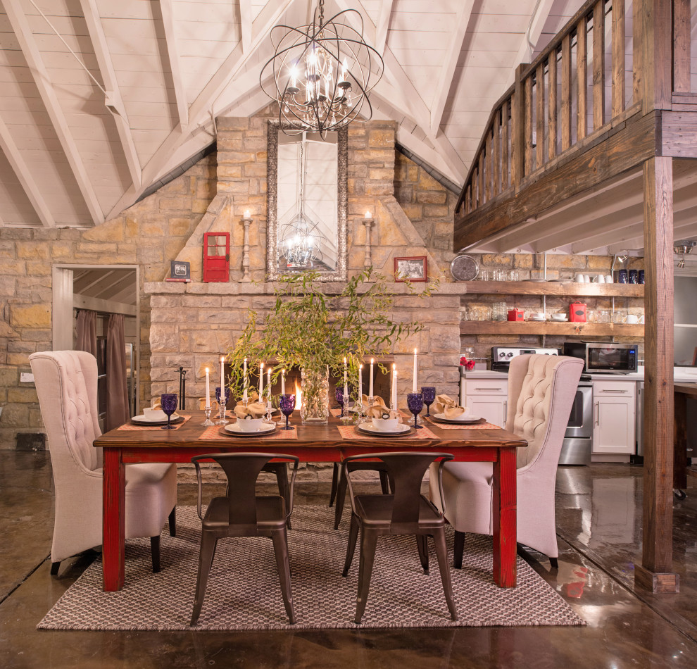 На фото: гостиная-столовая в стиле рустика с коричневыми стенами, бетонным полом, стандартным камином, фасадом камина из камня, коричневым полом и сводчатым потолком