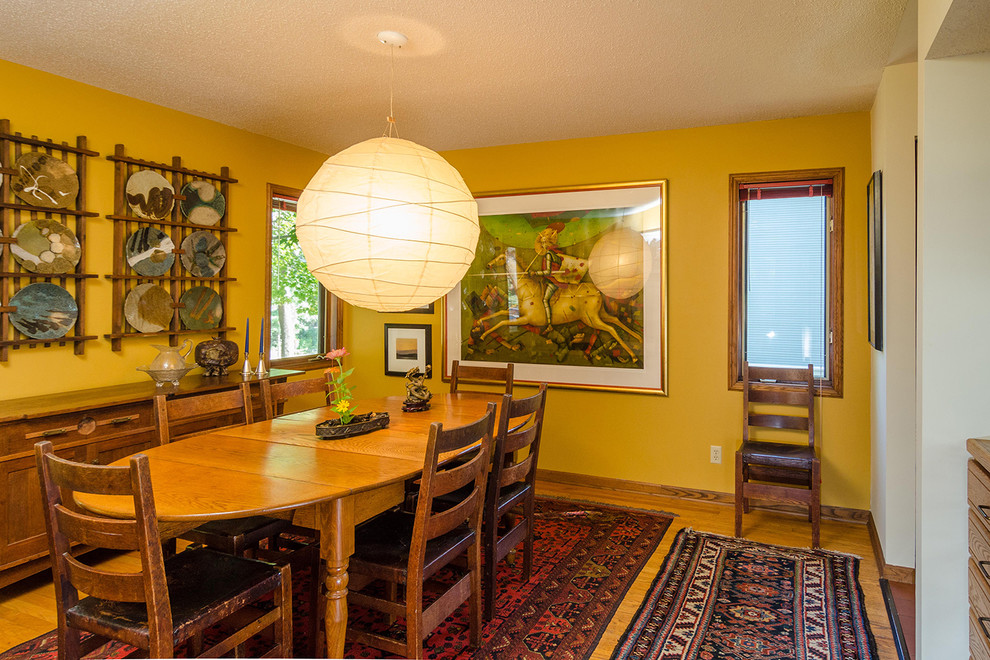 Inspiration pour une salle à manger bohème fermée et de taille moyenne avec un mur jaune, parquet clair et un sol marron.