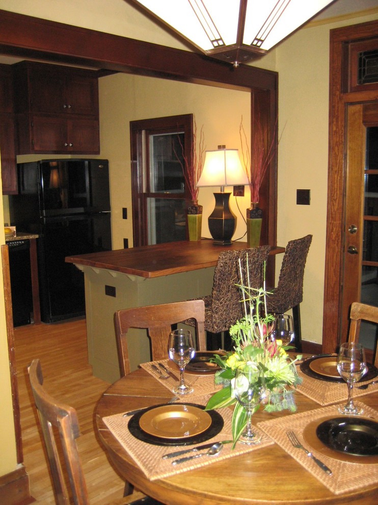 Réalisation d'une salle à manger ouverte sur la cuisine craftsman de taille moyenne avec un mur jaune, parquet clair et éclairage.