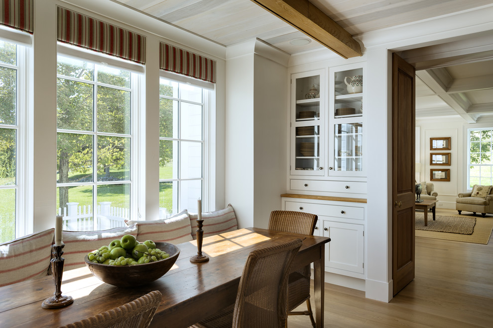 Imagen de comedor campestre con paredes blancas y suelo de madera en tonos medios