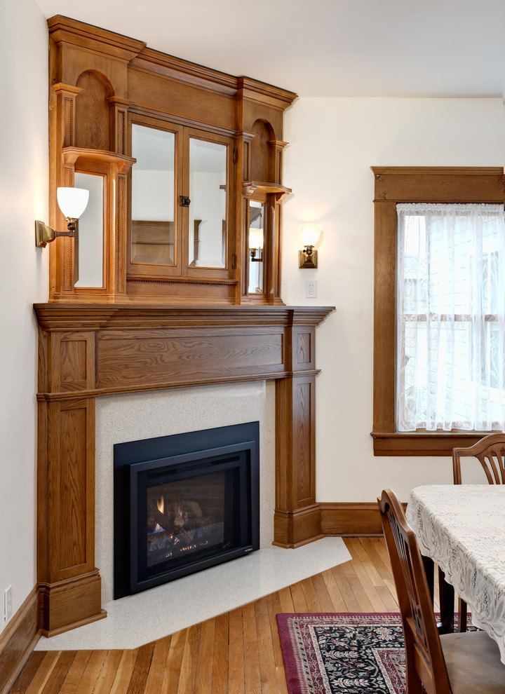Inspiration for a mid-sized timeless light wood floor kitchen/dining room combo remodel in Other with white walls, a corner fireplace and a stone fireplace