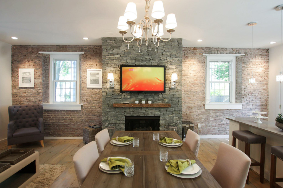 Large rustic open plan dining room in Boston with white walls, light hardwood flooring, a hanging fireplace, a stone fireplace surround and beige floors.