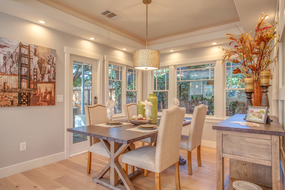 This is an example of a country open plan dining room in San Francisco with white walls, light hardwood flooring and no fireplace.