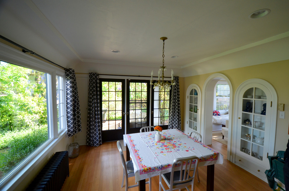 Cette image montre une salle à manger ouverte sur la cuisine traditionnelle avec un mur jaune et parquet clair.