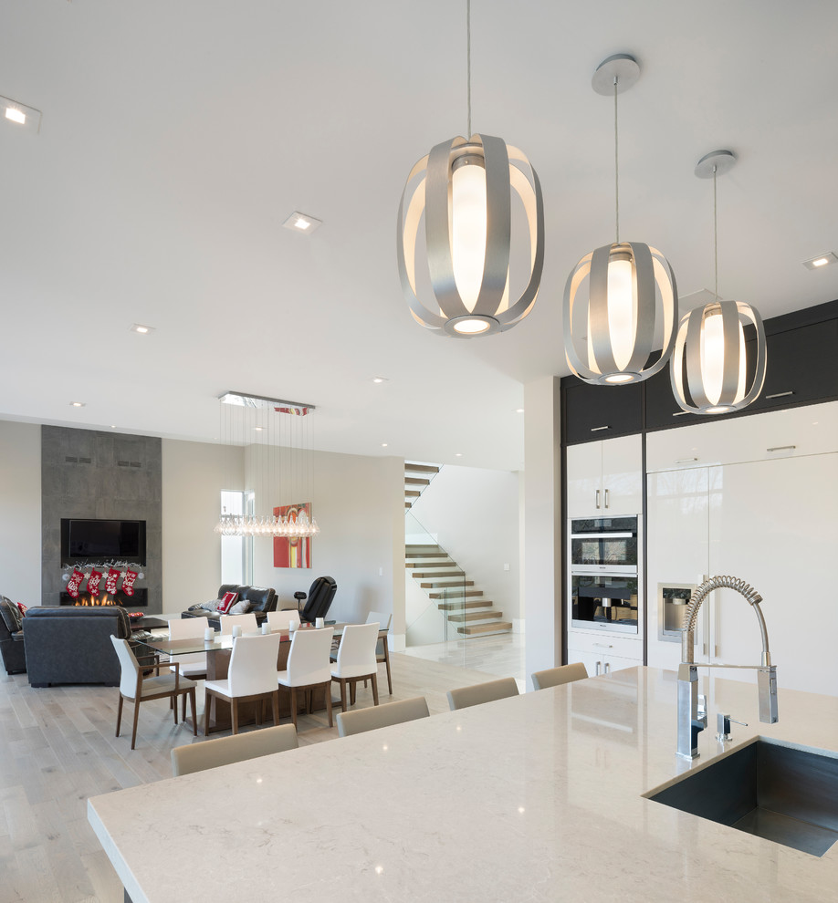 Exemple d'une très grande salle à manger ouverte sur la cuisine moderne avec un mur blanc, parquet clair, cheminée suspendue, un manteau de cheminée en béton et un sol blanc.