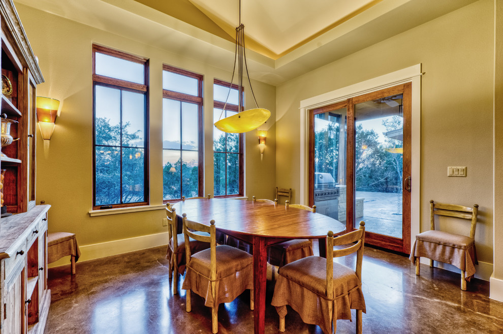 Foto di una sala da pranzo aperta verso la cucina boho chic di medie dimensioni con pavimento in cemento, nessun camino, pareti beige e pavimento marrone