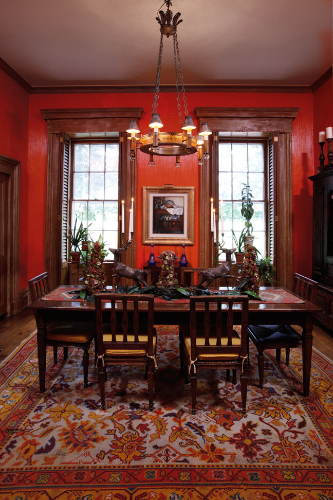На фото: столовая в классическом стиле с красными стенами, паркетным полом среднего тона и стандартным камином с