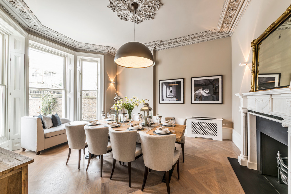 Large transitional light wood floor dining room photo in London with beige walls and a standard fireplace