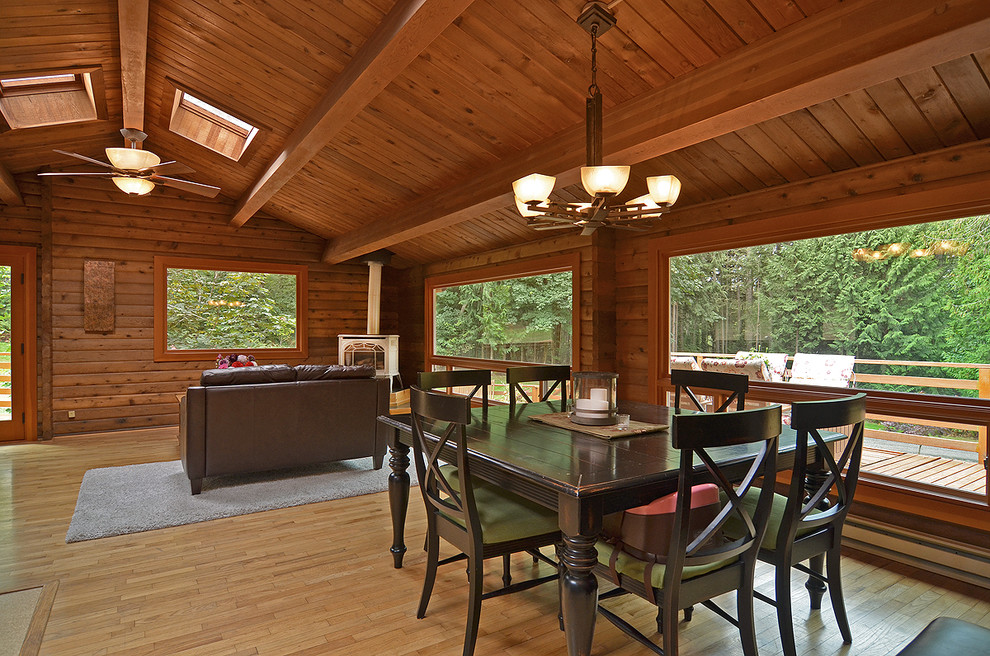 Réalisation d'une salle à manger ouverte sur le salon chalet de taille moyenne avec un sol en bois brun et un poêle à bois.