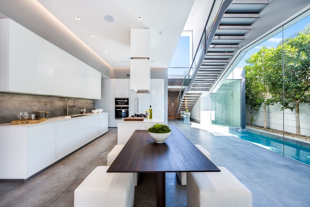 На фото: кухня-столовая в современном стиле с белыми стенами, бетонным полом и серым полом