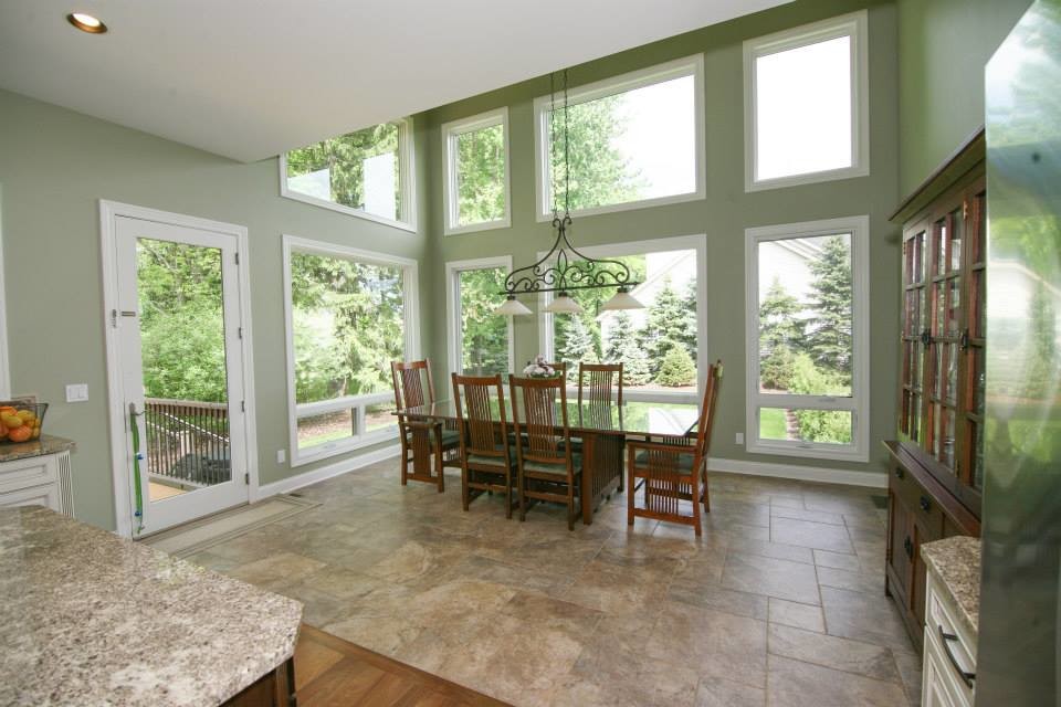 Immagine di una grande sala da pranzo aperta verso la cucina classica con pareti verdi e pavimento in gres porcellanato