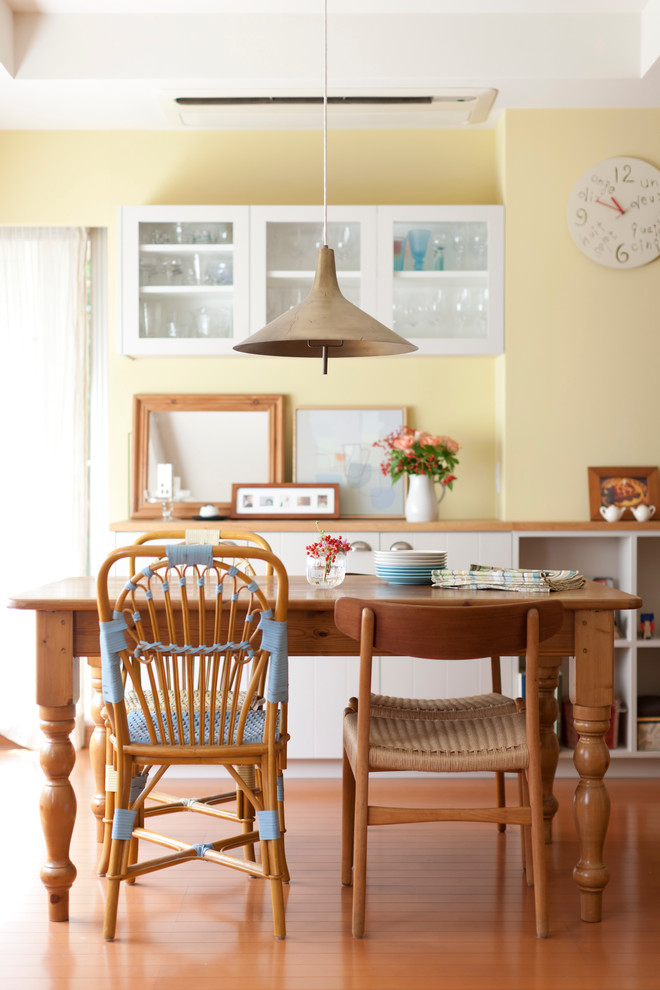 Esempio di una sala da pranzo aperta verso la cucina contemporanea di medie dimensioni con pareti gialle, pavimento in legno massello medio, nessun camino e pavimento marrone