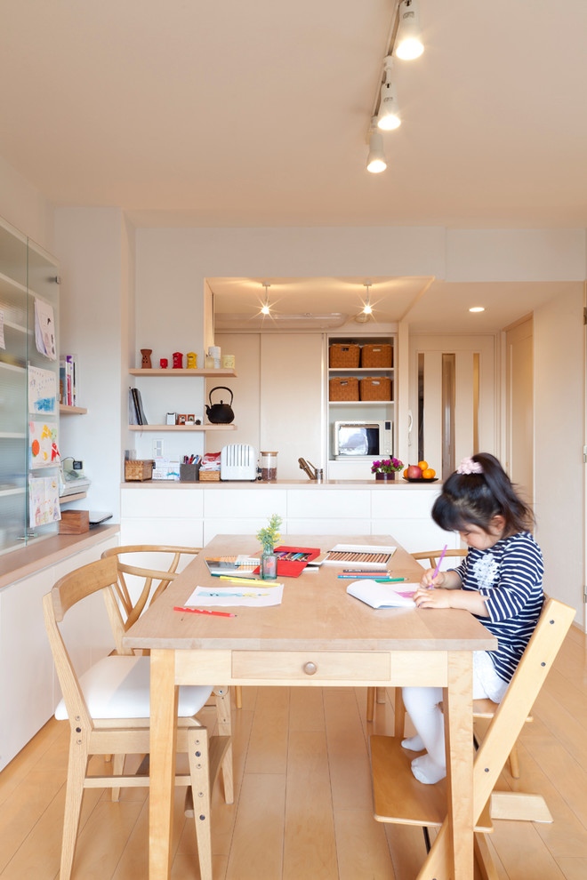 Cette photo montre une salle à manger ouverte sur la cuisine de taille moyenne avec un mur blanc, un sol en bois brun et aucune cheminée.