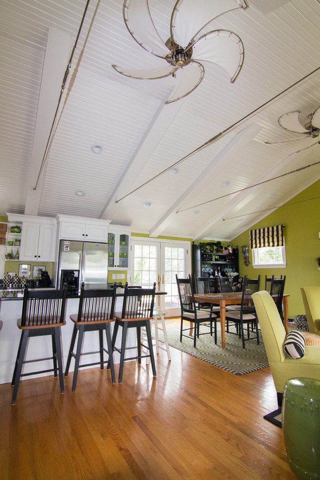 Foto di una sala da pranzo aperta verso il soggiorno stile marino con pareti verdi, pavimento in legno massello medio e camino classico