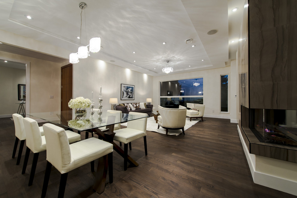 Imagen de comedor moderno grande abierto con paredes blancas, suelo de madera en tonos medios y chimenea de doble cara