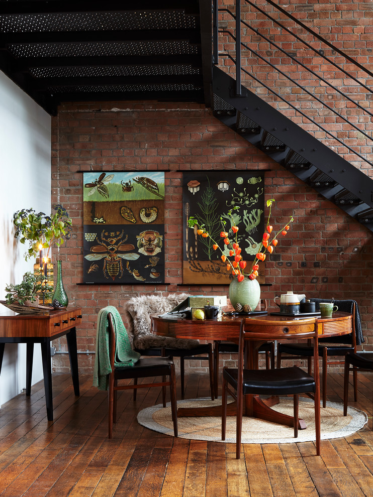 Esempio di una sala da pranzo aperta verso il soggiorno industriale con pavimento in legno massello medio e pareti rosse