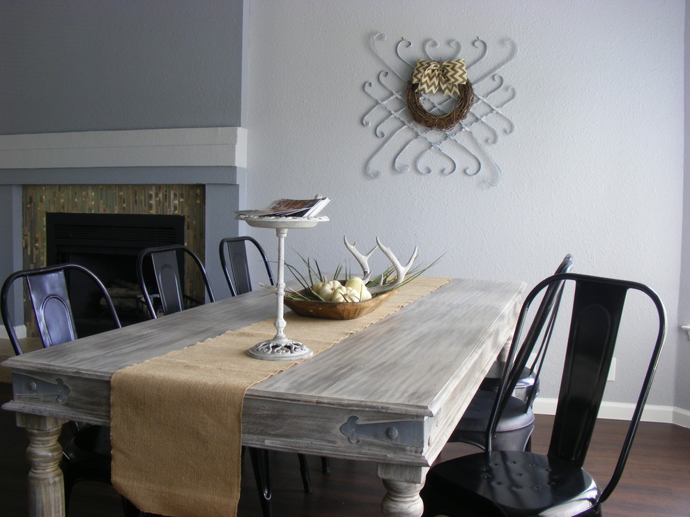 Exemple d'une salle à manger industrielle avec un mur gris, une cheminée standard et parquet foncé.