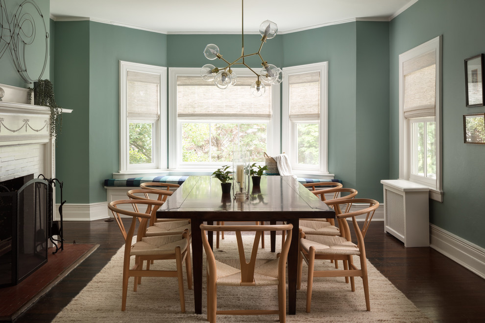 Example of a large beach style dark wood floor and brown floor dining room design in New York with green walls and a standard fireplace