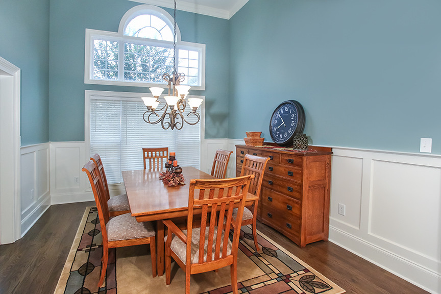 Cette photo montre une salle à manger craftsman fermée et de taille moyenne avec un mur bleu, un sol en bois brun et aucune cheminée.