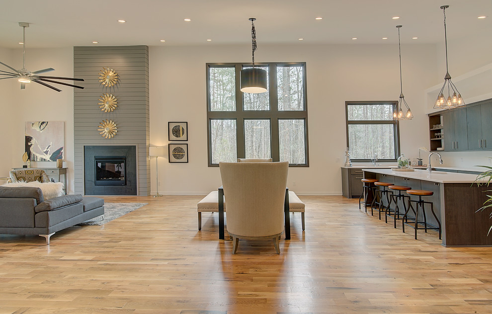 Foto di una grande sala da pranzo aperta verso il soggiorno minimalista con pareti bianche e parquet chiaro