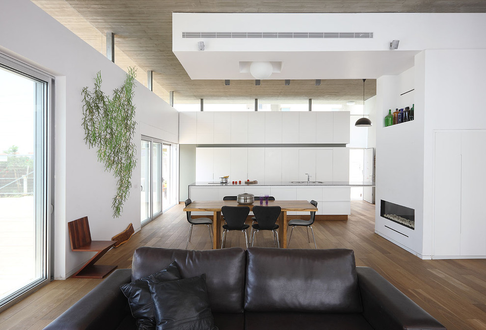 Ejemplo de comedor minimalista de tamaño medio abierto con paredes blancas, suelo de madera oscura, chimenea lineal y marco de chimenea de yeso
