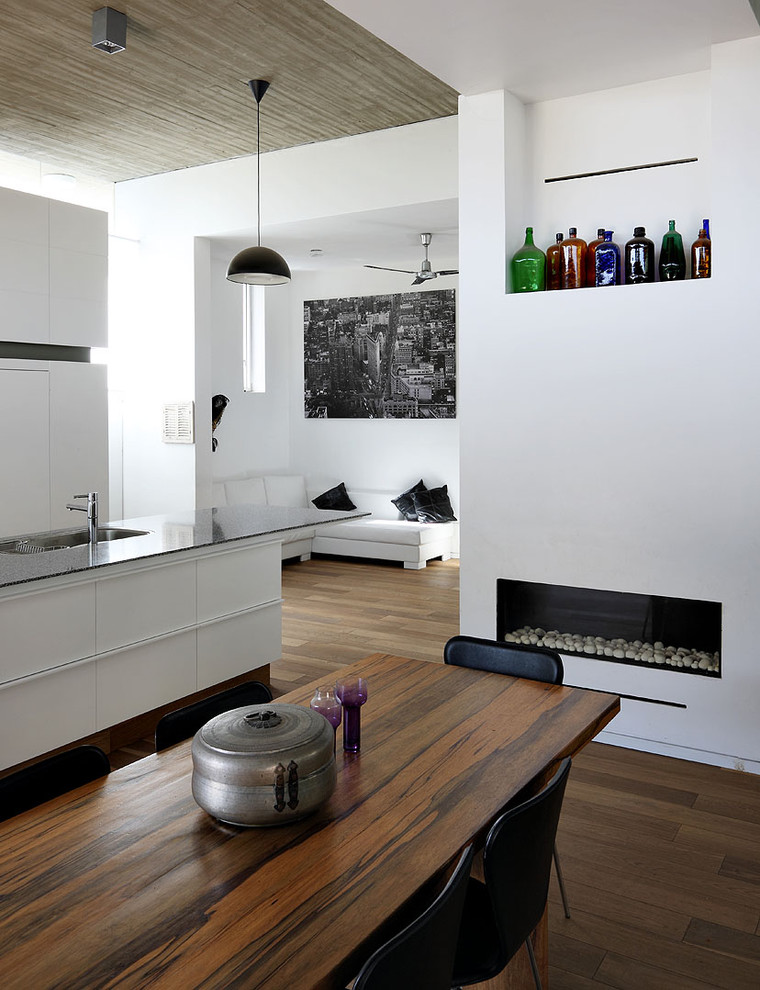 Mid-sized minimalist dark wood floor dining room photo in Tel Aviv with white walls, a ribbon fireplace and a plaster fireplace