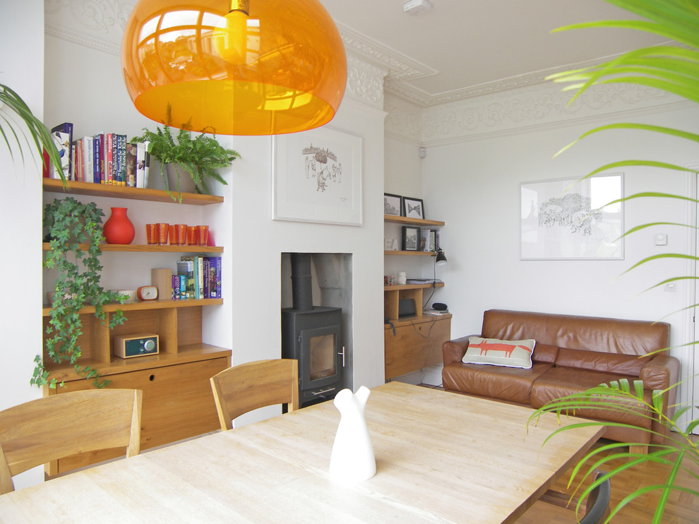 Idee per una sala da pranzo moderna con pavimento in legno massello medio e stufa a legna