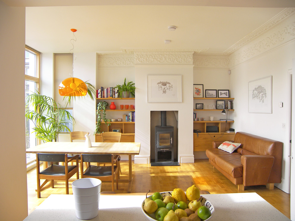Immagine di una sala da pranzo aperta verso il soggiorno contemporanea con pavimento in legno massello medio, stufa a legna e pareti bianche