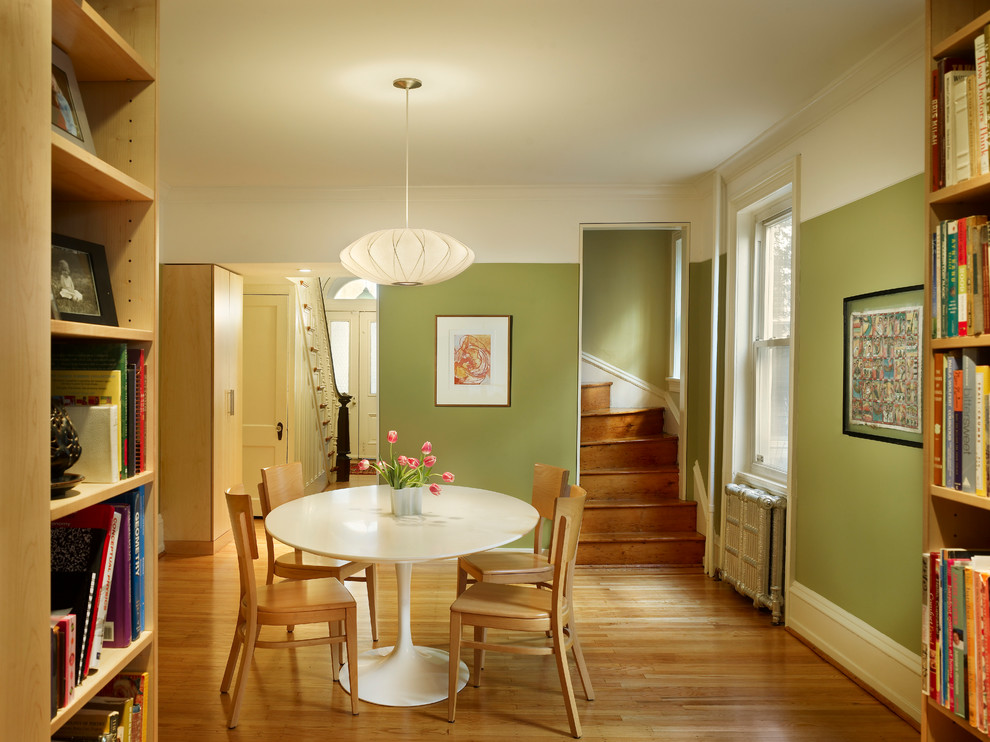 Cette image montre une salle à manger ouverte sur la cuisine craftsman de taille moyenne avec un mur vert, un sol en bois brun et un sol marron.