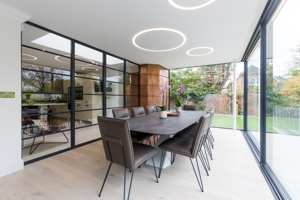 Inspiration for a medium sized contemporary enclosed dining room in London with light hardwood flooring and beige floors.