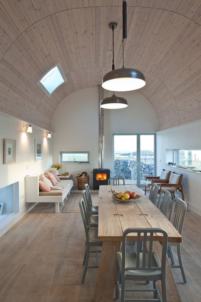 Immagine di una sala da pranzo aperta verso il soggiorno contemporanea di medie dimensioni con pareti bianche, parquet chiaro e stufa a legna