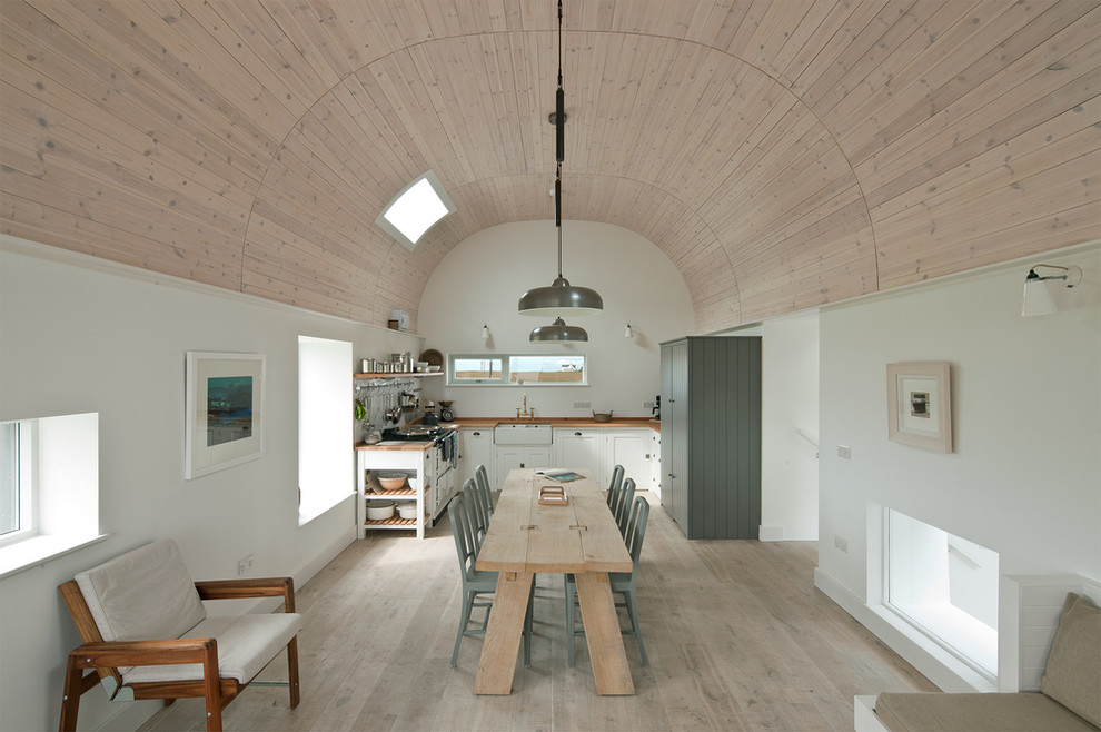 Esempio di una sala da pranzo aperta verso il soggiorno stile marinaro con pareti bianche e parquet chiaro