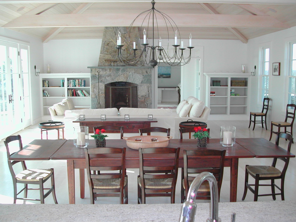 Cette image montre une salle à manger ouverte sur le salon traditionnelle de taille moyenne avec un mur blanc, parquet clair, une cheminée standard, un manteau de cheminée en pierre et un sol beige.