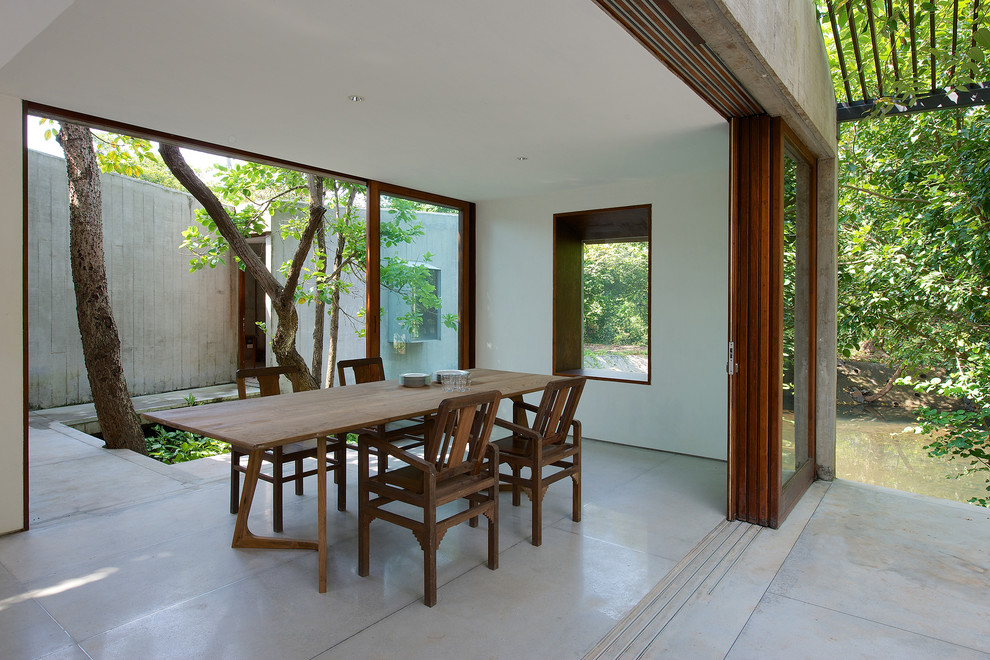 Ispirazione per una piccola sala da pranzo aperta verso la cucina minimal con pareti bianche e pavimento in cemento