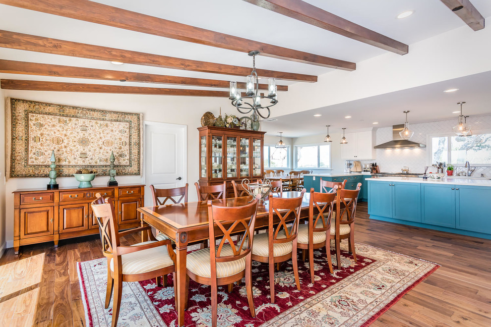 Aménagement d'une salle à manger ouverte sur la cuisine classique de taille moyenne avec un mur blanc, un sol en bois brun, une cheminée double-face et un manteau de cheminée en carrelage.